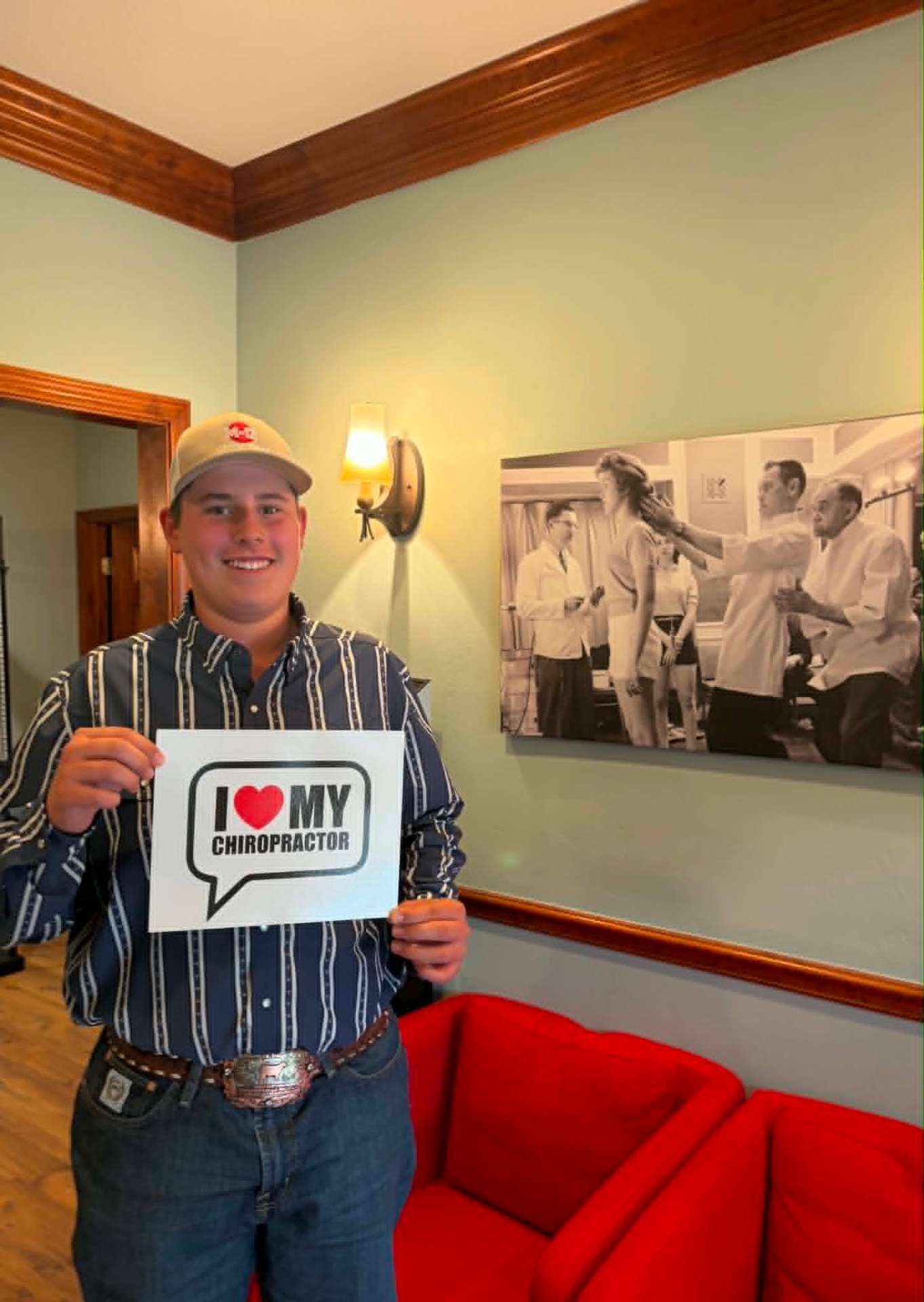 Patient holding an I Love My Chiropractor sign in the waiting room